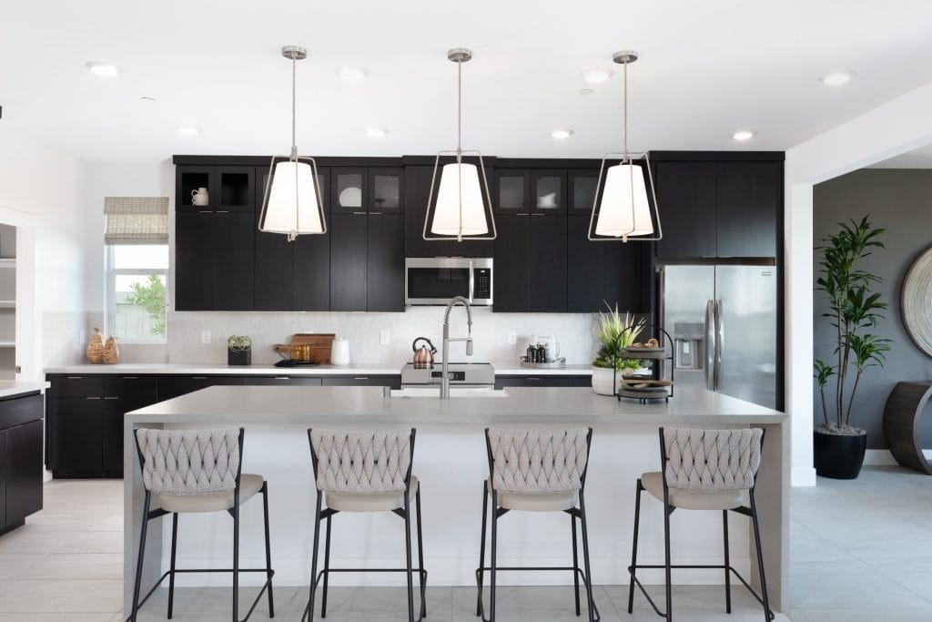 Black custom upper cabinets with white island and woven counter stools in a modern kitchen