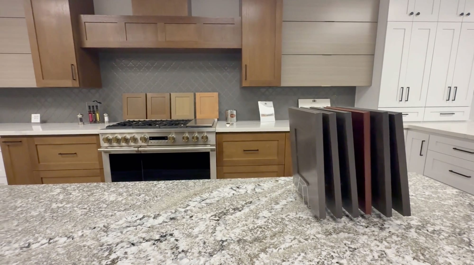 Custom cabinet door style and stain finish samples on a granite countertop in a cabinet showroom