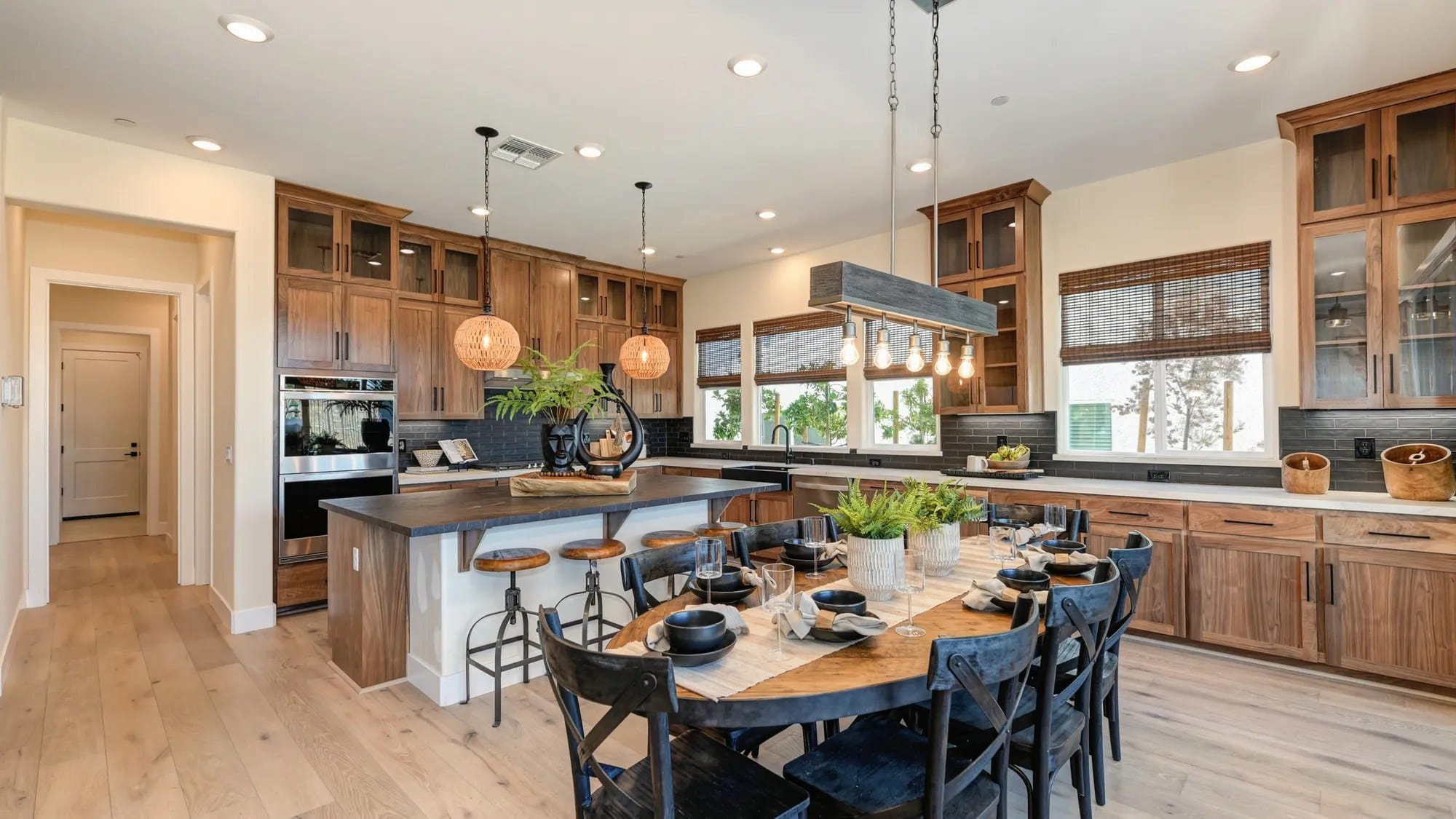 Custom stained wood kitchen cabinets with glass-front uppers, black island and pendant lighting in a Sacramento-area home