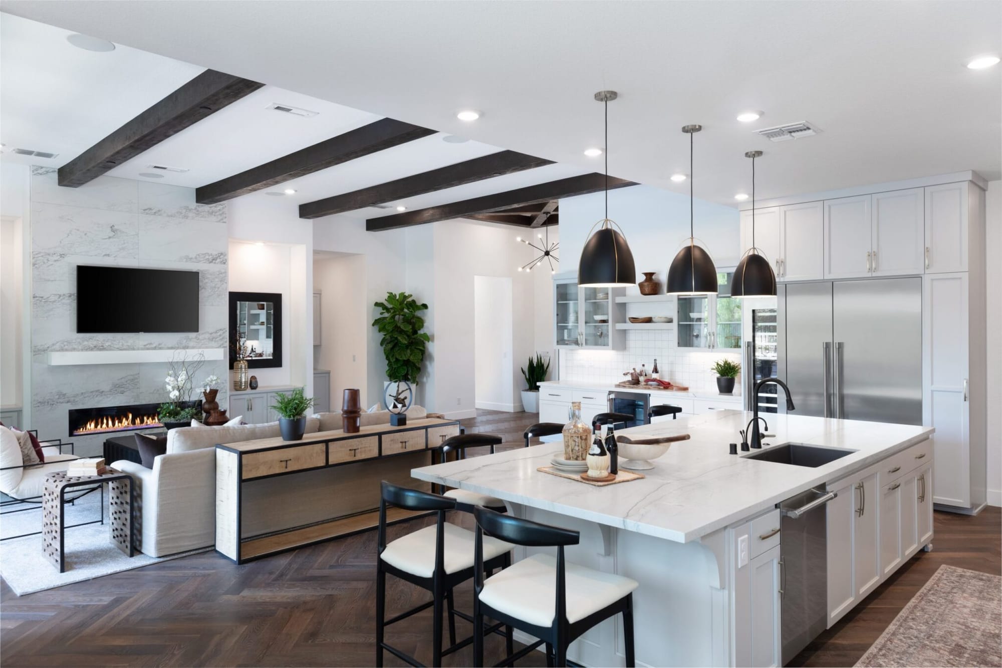 Open-concept kitchen remodel with white custom cabinets, large island and beamed ceiling open to the living room