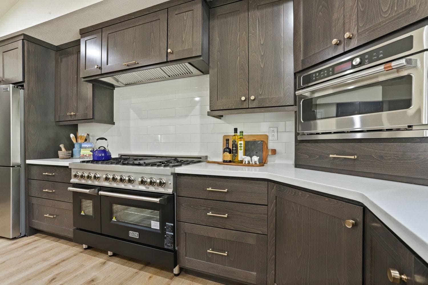 Dark stained cabinets and wall ovens beside a professional range