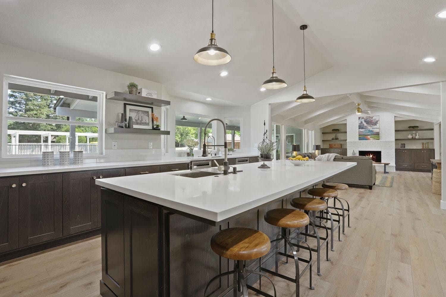 Long white quartz kitchen island with espresso base cabinets and pendant lights in Roseville