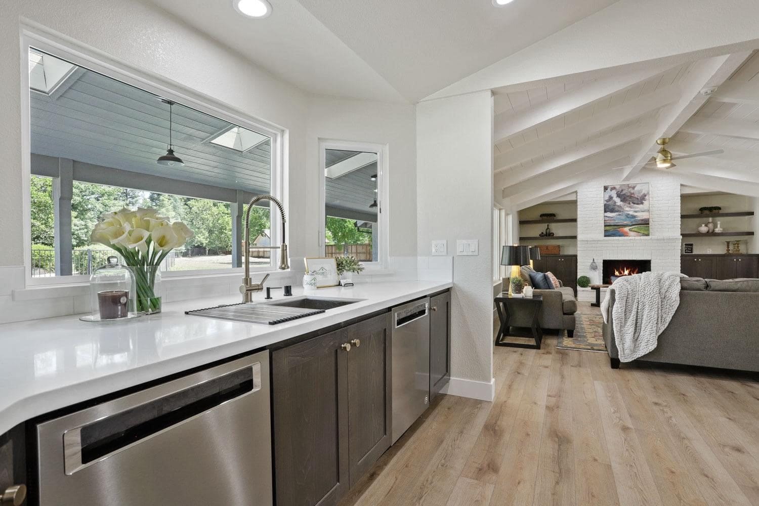 Kitchen sink run with espresso cabinets and white quartz countertops under a window