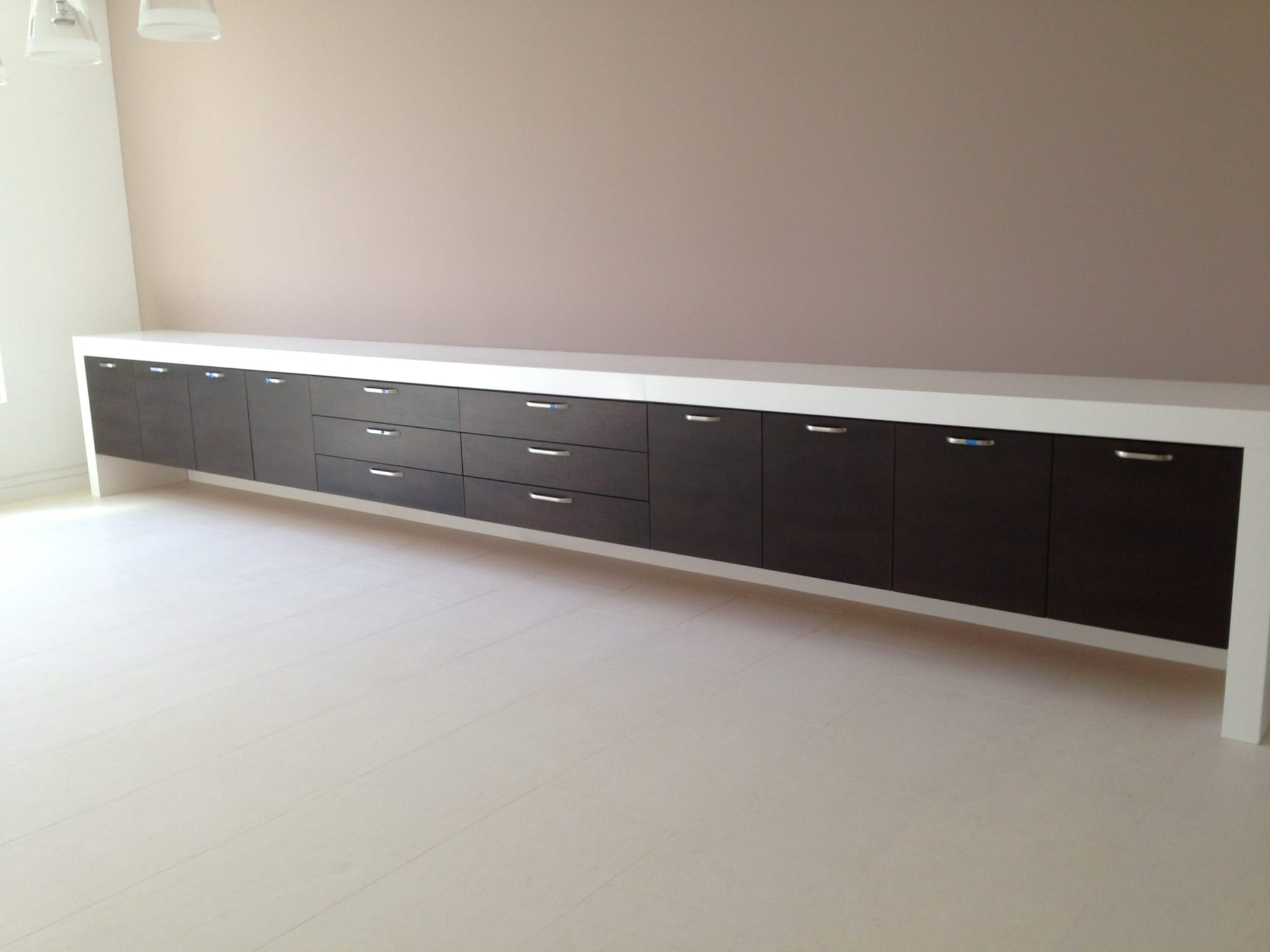 Wall-length espresso slab-door cabinets with drawers and quartz top