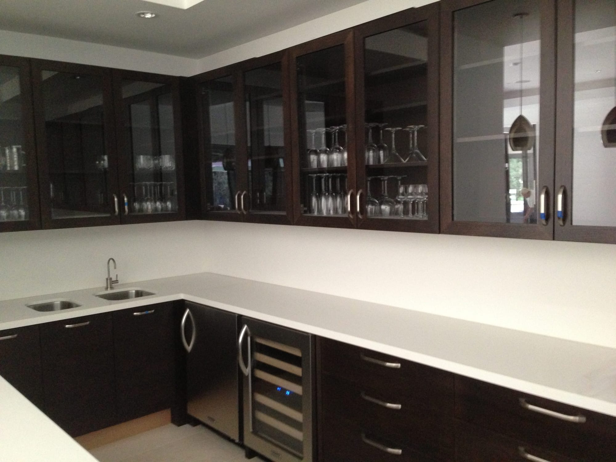 Custom wet bar with glass-front upper cabinets, stemware storage and wine fridge