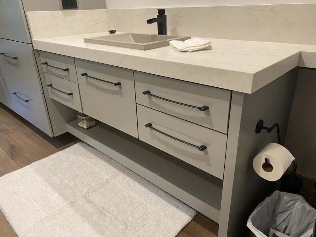 Gray painted floating bathroom vanity with open shelf and black pulls