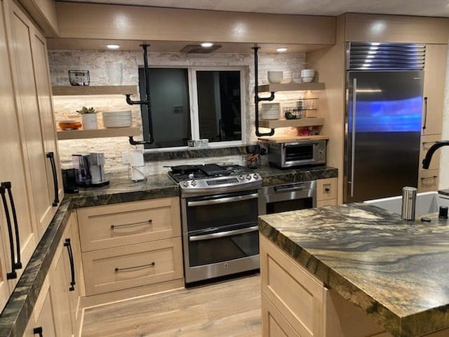 Range wall with white oak base cabinets, floating shelves and stacked stone backsplash