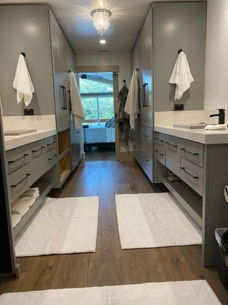 Primary bathroom with custom gray vanities and tall linen cabinets