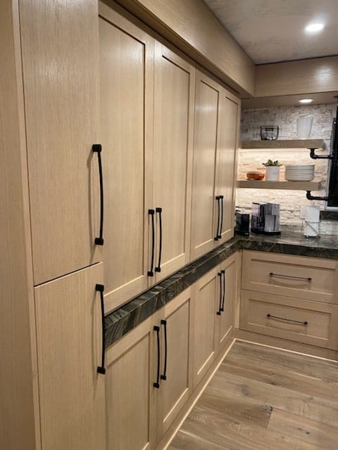 Floor-to-ceiling white oak pantry cabinets with long matte black pulls