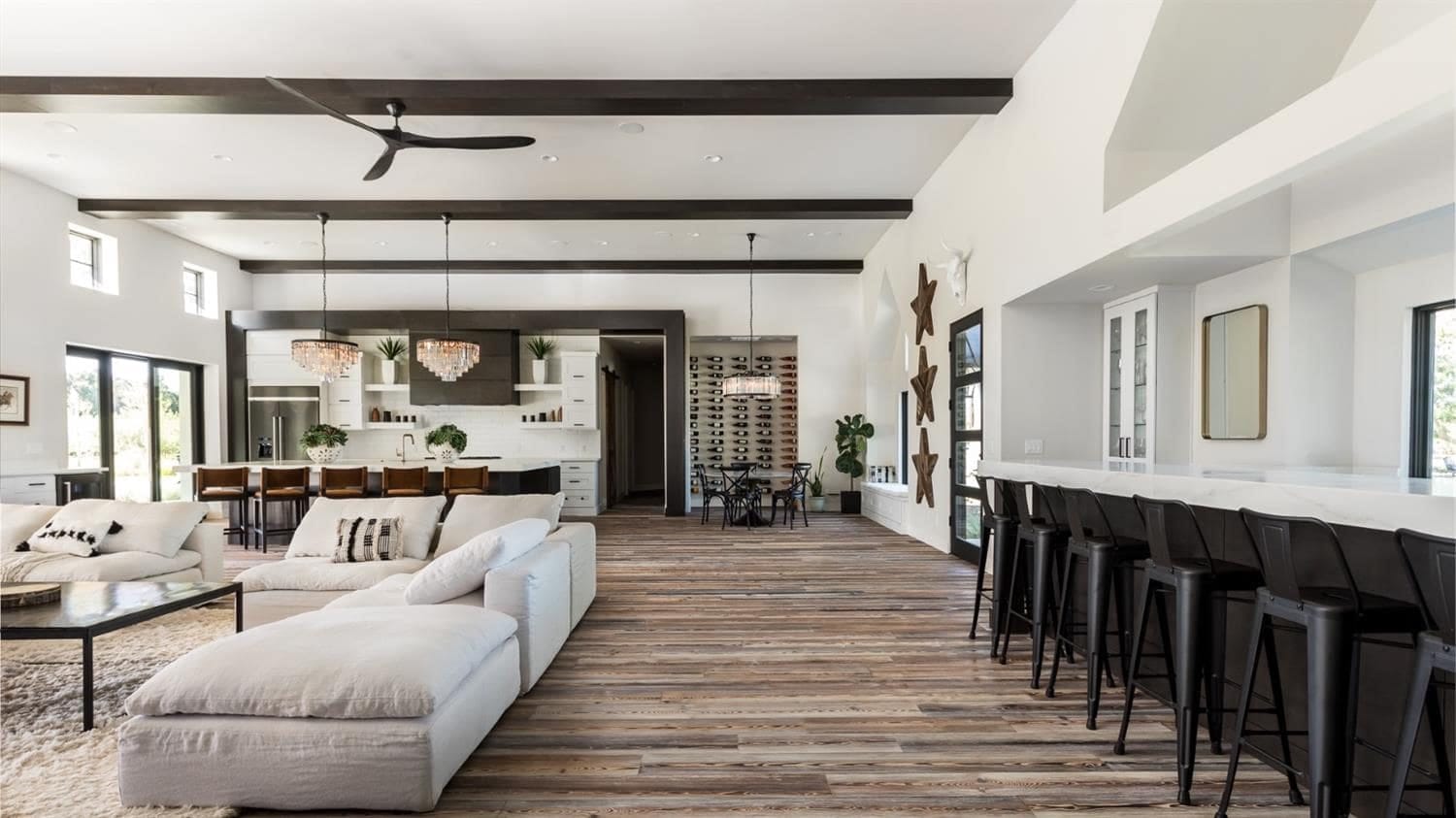 Open great room with white kitchen cabinets, long island and beamed ceiling in Woodland, CA