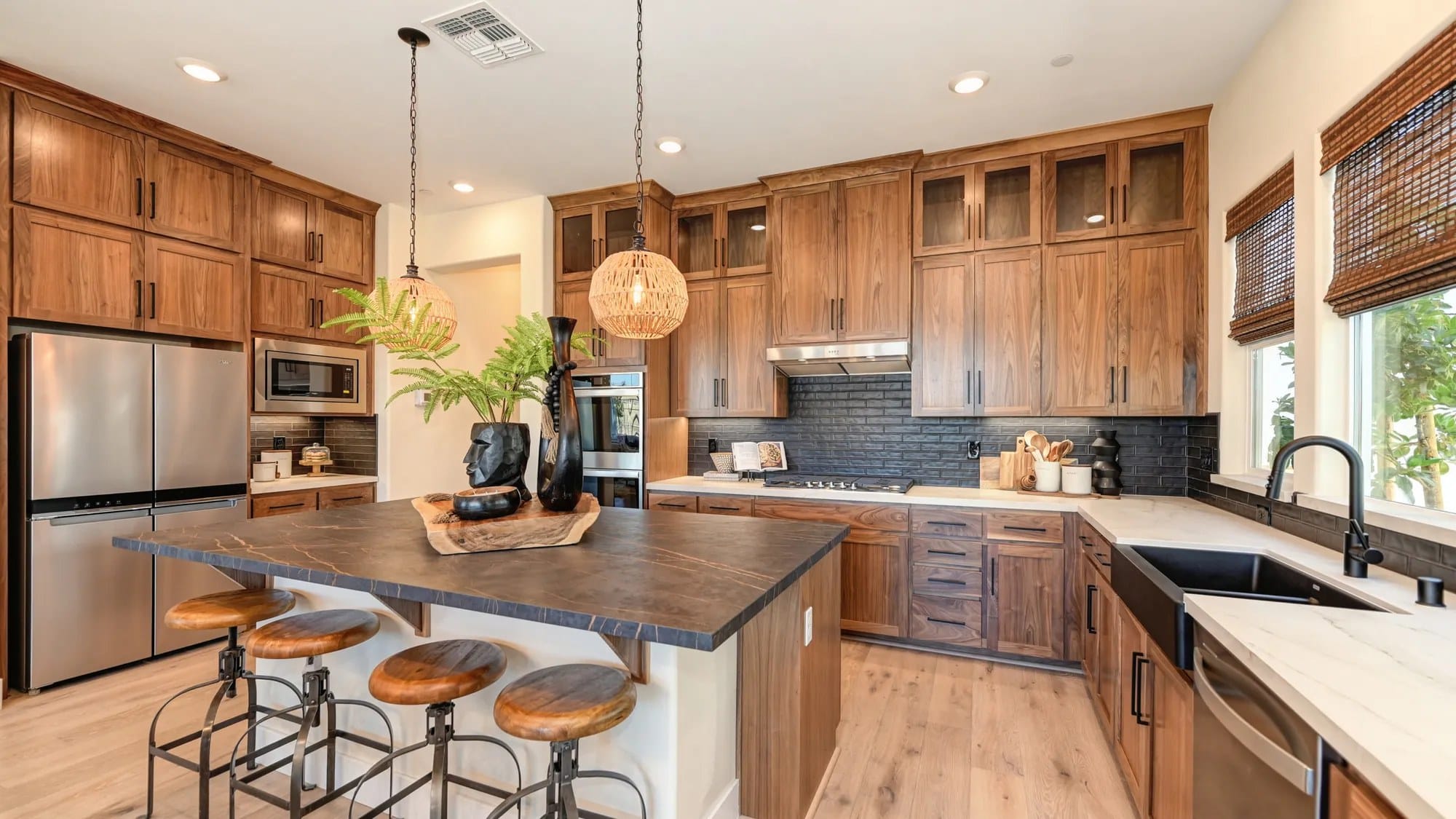 Stained wood kitchen cabinets with glass uppers and dark countertop island with wood stools