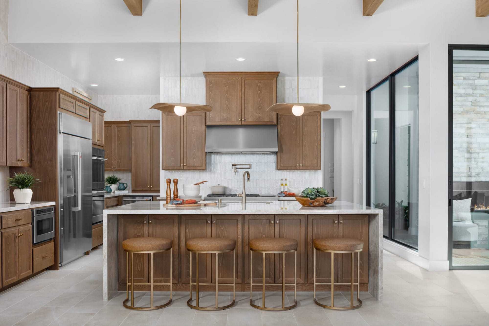 Walnut stained kitchen cabinets with white waterfall quartz island and brass counter stools